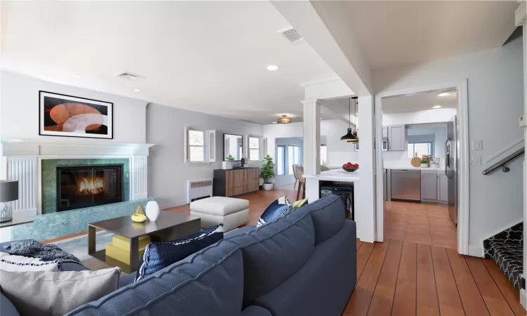 Living area with a high end fireplace, visible vents, radiator, and wood finished floors