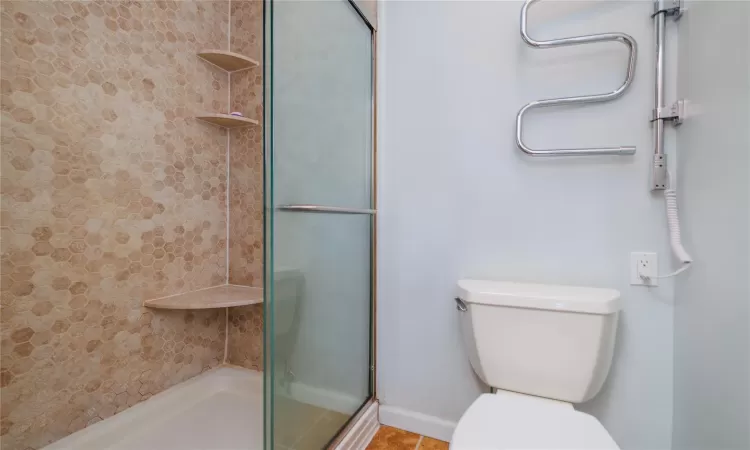 Primary Bathroom with tile patterned flooring, baseboards, toilet, a stall shower, and vanity