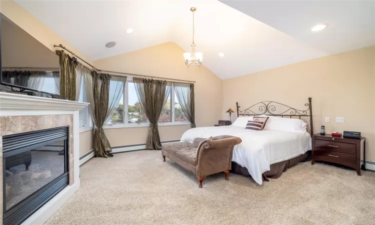 Primary Bedroom with panoramic views of water, a fireplace, carpet, and vaulted ceiling