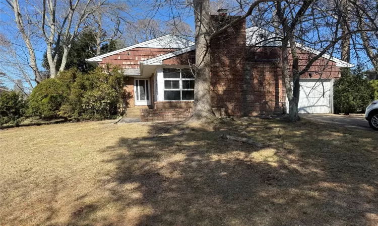 View of front facade featuring a front lawn, a garage, and brick siding