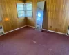 Unfurnished room with baseboards, carpet, and wooden walls