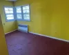 Carpeted empty room with radiator and baseboards