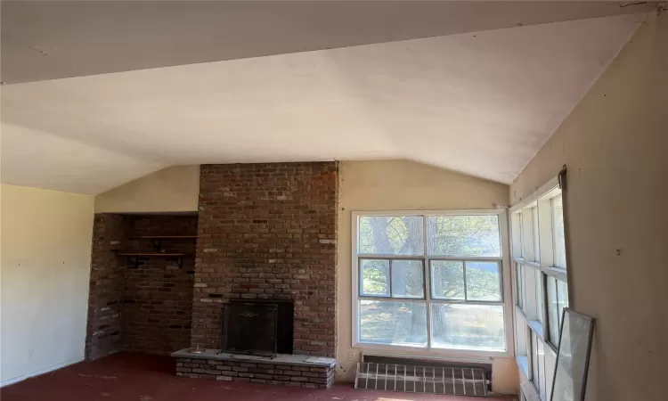 Unfurnished living room with lofted ceiling and a fireplace