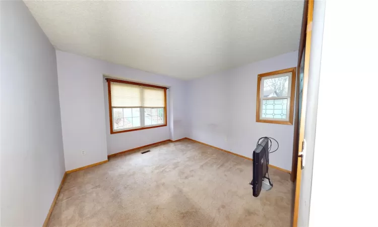 Unfurnished room with visible vents, carpet floors, a textured ceiling, and baseboards