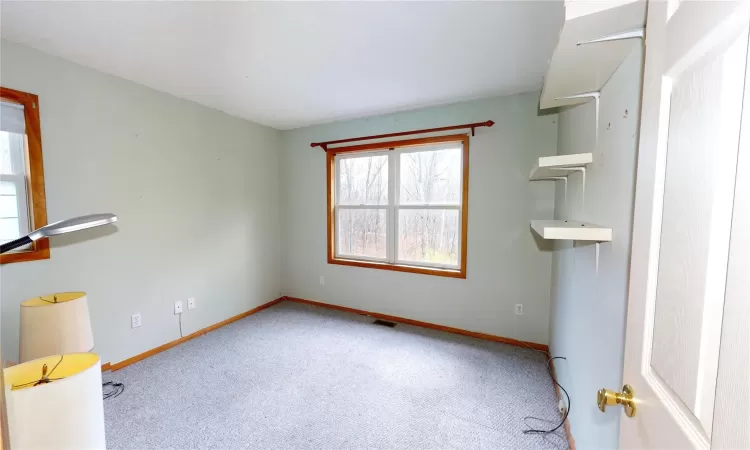 Carpeted empty room with visible vents and baseboards