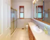 Full bathroom with tile patterned flooring, wainscoting, a stall shower, and vanity