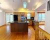 Kitchen with lofted ceiling with skylight, light wood finished floors, appliances with stainless steel finishes, and a center island