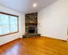 Unfurnished living room with visible vents, lofted ceiling, wood finished floors, a stone fireplace, and baseboards