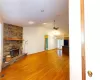 Unfurnished living room with visible vents, light wood-style flooring, ceiling fan, a stone fireplace, and vaulted ceiling