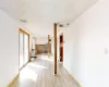 Hall with visible vents, light wood-style flooring, baseboards, and a drop ceiling