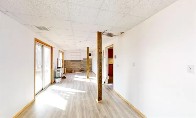 Hall with visible vents, light wood-style flooring, baseboards, and a drop ceiling