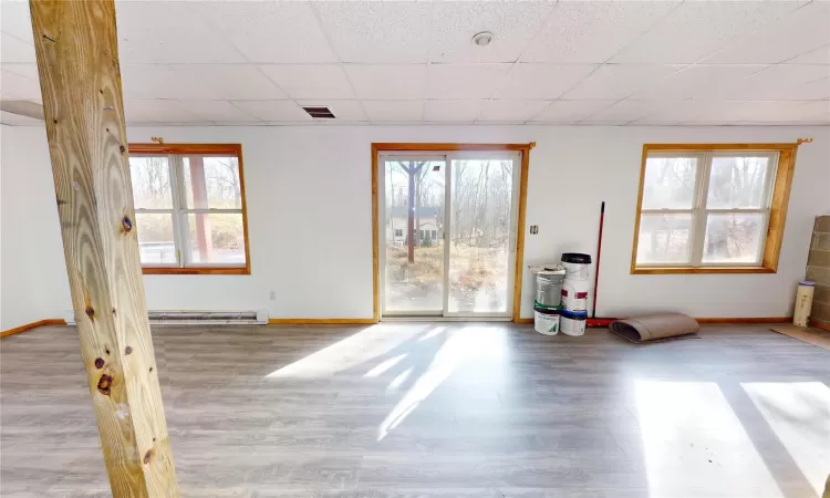 Spare room featuring a wealth of natural light, visible vents, a paneled ceiling, and a baseboard radiator