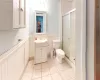 Bathroom featuring tile patterned floors, toilet, a wainscoted wall, and a stall shower