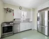 Kitchen featuring backsplash, light countertops, white cabinets, stainless steel appliances, and a sink