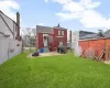 Back of house featuring entry steps, a fenced backyard, a lawn, and a chimney