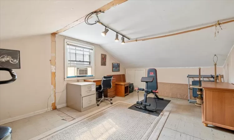 Home office with cooling unit, baseboards, rail lighting, lofted ceiling, and light floors