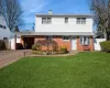 View of front facade with brick siding, a chimney, a front lawn, and fence