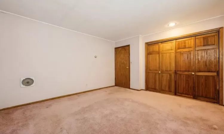 Unfurnished bedroom featuring baseboards, light carpet, and a closet