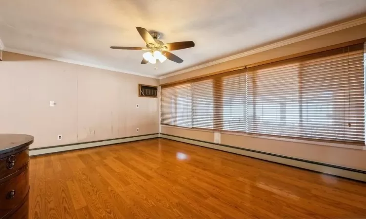 Empty room with plenty of natural light, ornamental molding, a ceiling fan, and light wood finished floors