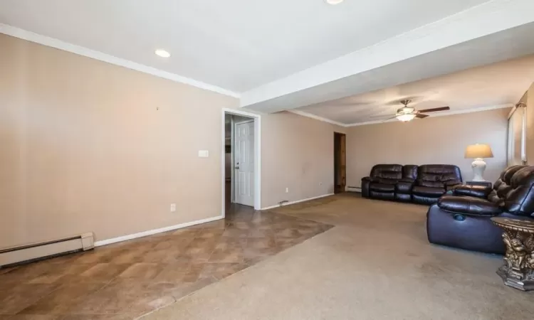 Carpeted living room with crown molding, baseboards, and a baseboard radiator