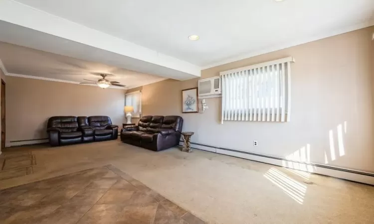 Carpeted living room featuring a baseboard radiator, a wall mounted AC, ceiling fan, a baseboard heating unit, and crown molding