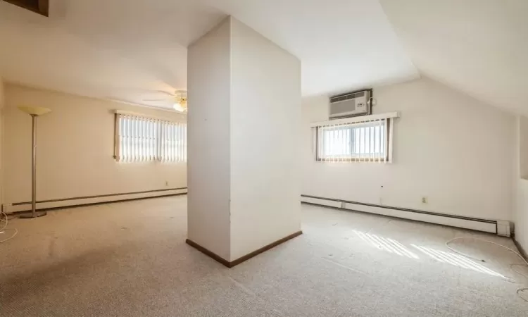 Bonus room featuring carpet flooring, a wall mounted air conditioner, and a baseboard radiator