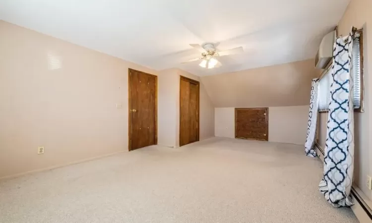 Additional living space featuring an AC wall unit, carpet, a ceiling fan, and vaulted ceiling