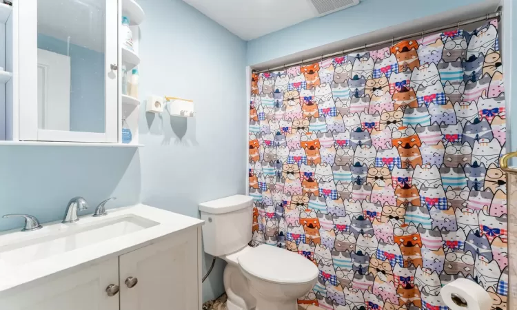 Bathroom with a shower with shower curtain, visible vents, toilet, and vanity