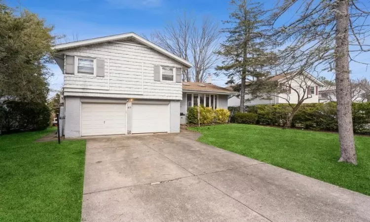 Split level home with driveway, an attached garage, and a front yard