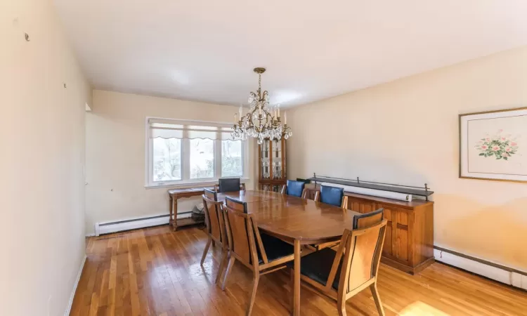 Dining area featuring baseboard heating, an inviting chandelier, baseboards, and light wood-style floors