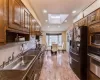 Kitchen with lofted ceiling with skylight, black appliances, a sink, tasteful backsplash, and recessed lighting