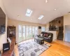 Living room featuring stairs, vaulted ceiling, baseboard heating, recessed lighting, and wood finished floors