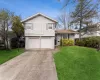 Split level home with a front lawn, concrete driveway, brick siding, and a garage