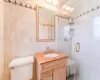 Bathroom with tile walls, a shower stall, toilet, and vanity