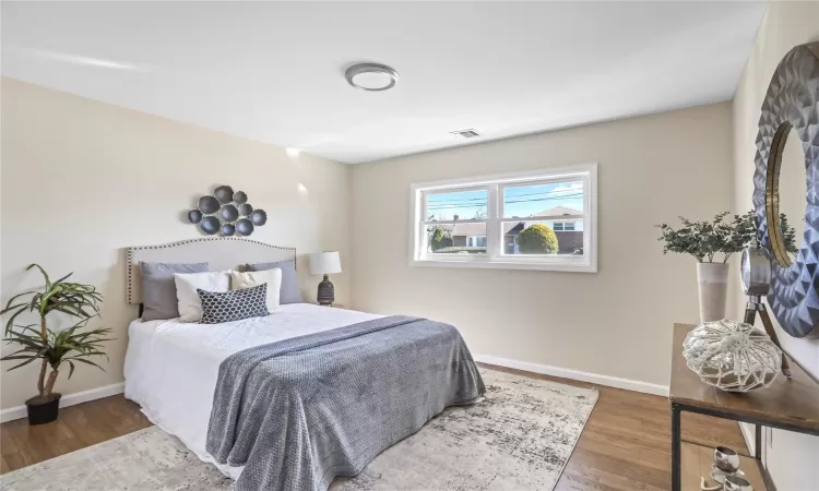 Bedroom featuring visible vents, baseboards, and wood finished floors