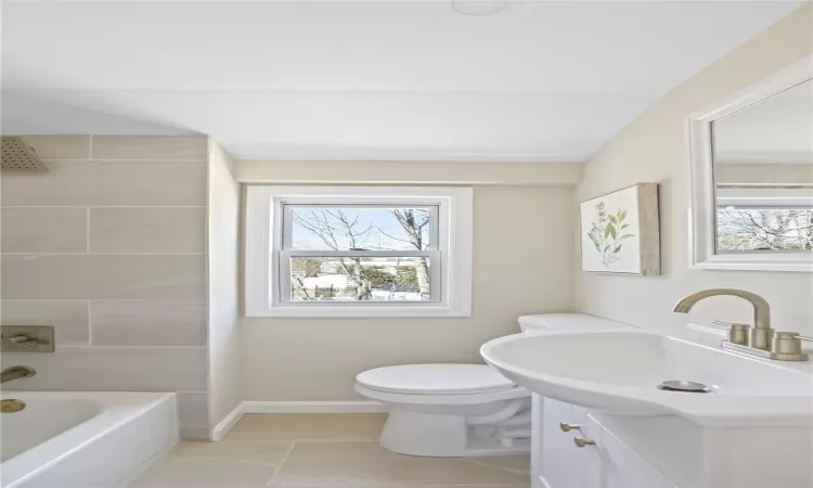 Bathroom featuring a wealth of natural light, baseboards, toilet, and vanity