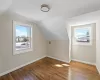 Additional living space with hardwood / wood-style flooring, visible vents, baseboards, and lofted ceiling