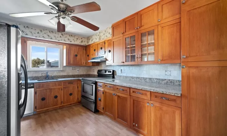 Kitchen featuring under cabinet range hood, stainless steel appliances, and brown cabinetry