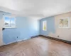 Unfurnished room with baseboard heating and lofted ceiling