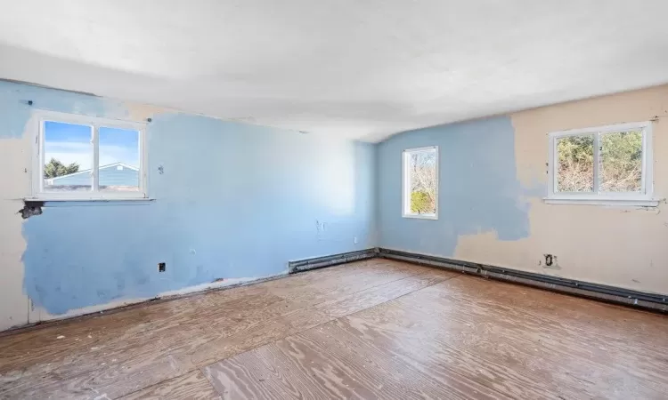 Unfurnished room with baseboard heating and lofted ceiling