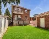 Rear view of property with a lawn, central AC, a fenced backyard, a balcony, and brick siding