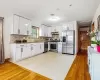 Kitchen featuring tasteful backsplash, under cabinet range hood, stainless steel appliances, light wood-style floors, and white cabinetry