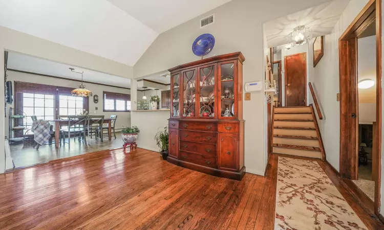 Dining room featuring visible vents, a chandelier, stairs, lofted ceiling, and wood finished floors