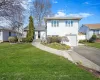 Tri-level home featuring aphalt driveway, a front lawn, and an attached garage