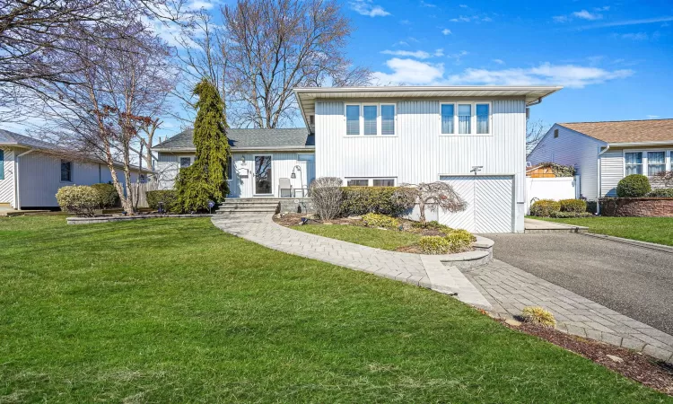 Tri-level home featuring aphalt driveway, a front lawn, and an attached garage