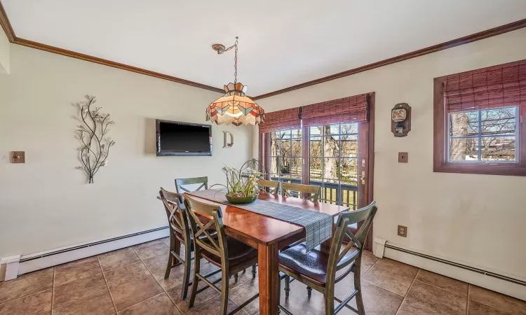 Tiled dining space featuring baseboard heating and crown molding