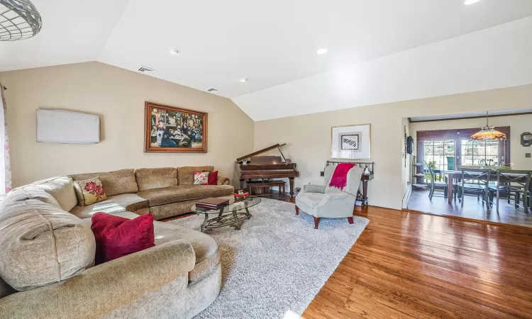 Living room with recessed lighting, visible vents, lofted ceiling, and wood finished floors