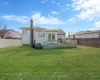 Back of property featuring a deck, a lawn, a fenced backyard, and a chimney