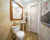 Bathroom with toilet, crown molding, baseboards, and a sink