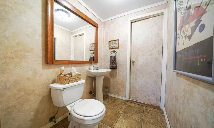 Bathroom with toilet, crown molding, baseboards, and a sink